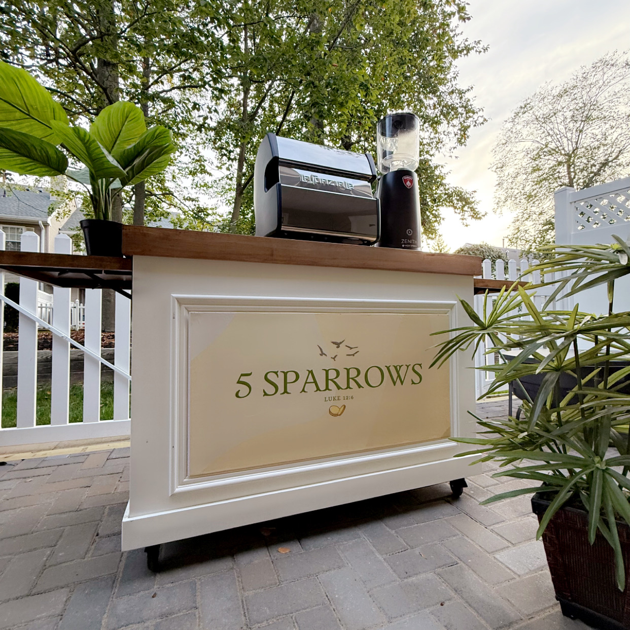 A couple posing with the 5 Sparrows coffee cart at a wedding event