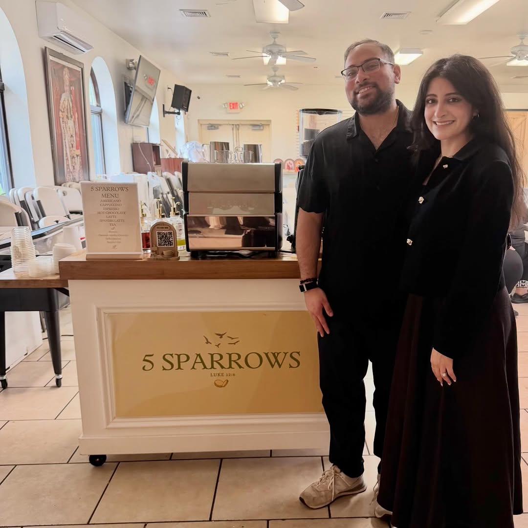 A couple posing with the 5 Sparrows coffee cart at a wedding event